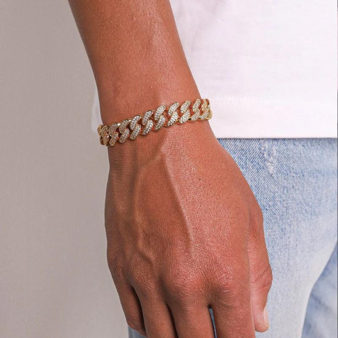 Men's model showcasing the Iced Cuban Link Bracelet in 18K Gold with 12MM links, featuring a bold design with sparkling gemstones for a powerful and sophisticated look.