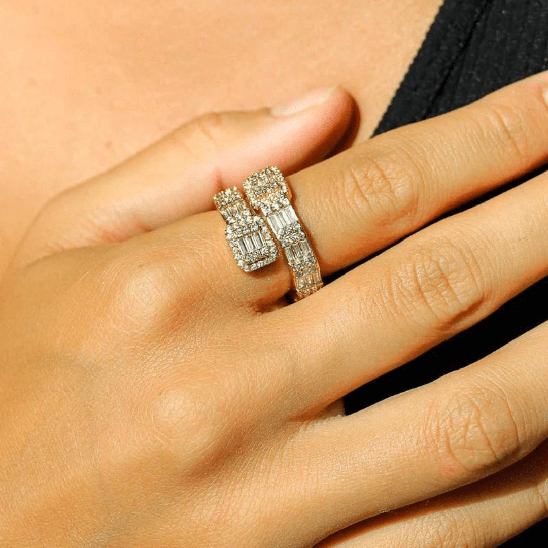 Model's hand adorned with an 18k gold baguette ring, highlighting the elegant row of baguette-cut gemstones against a contemporary, fashionable backdrop.