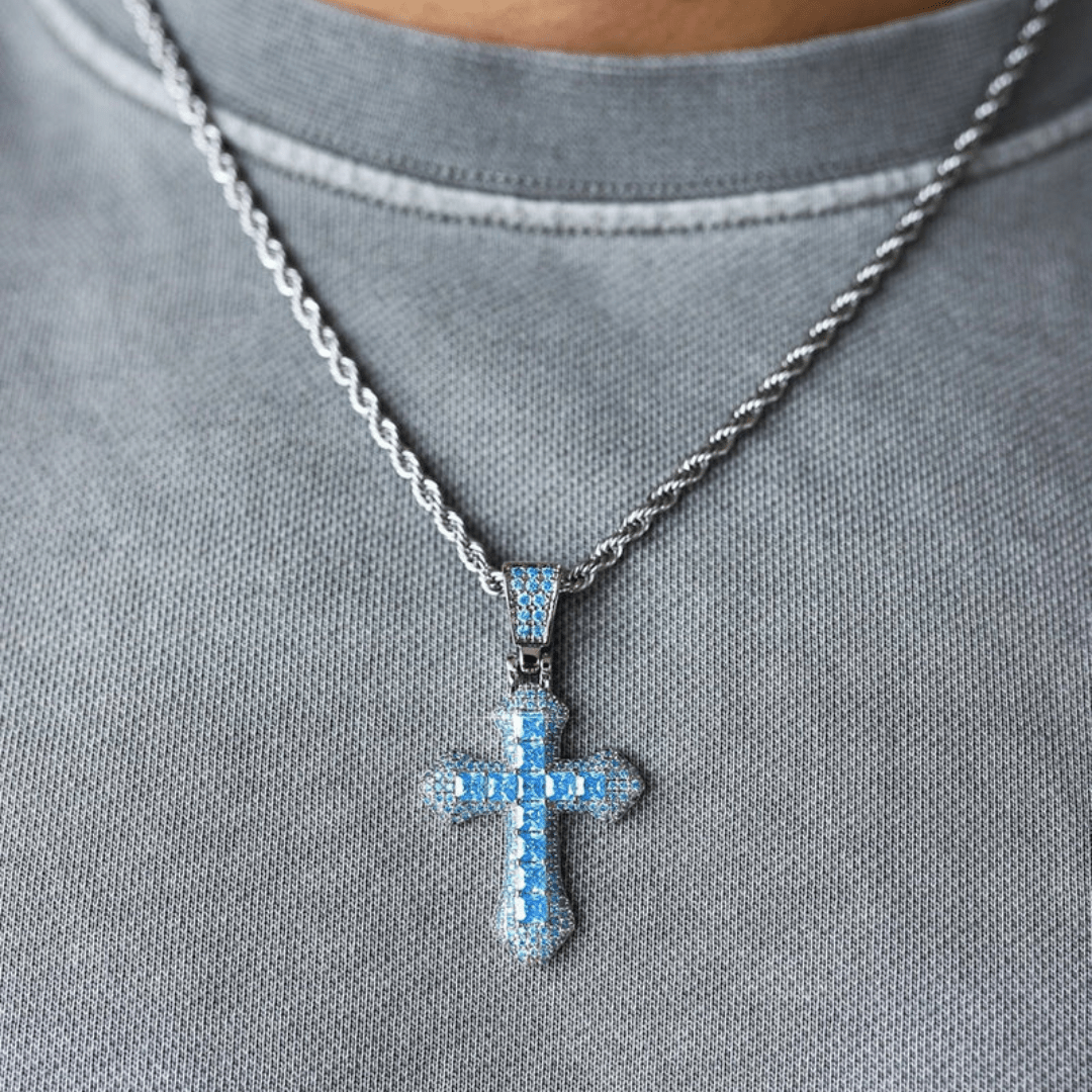 Model wearing a white gold cross pendant with striking blue gemstones, displayed on a delicate chain around the neck, complementing a stylish and elegant outfit.