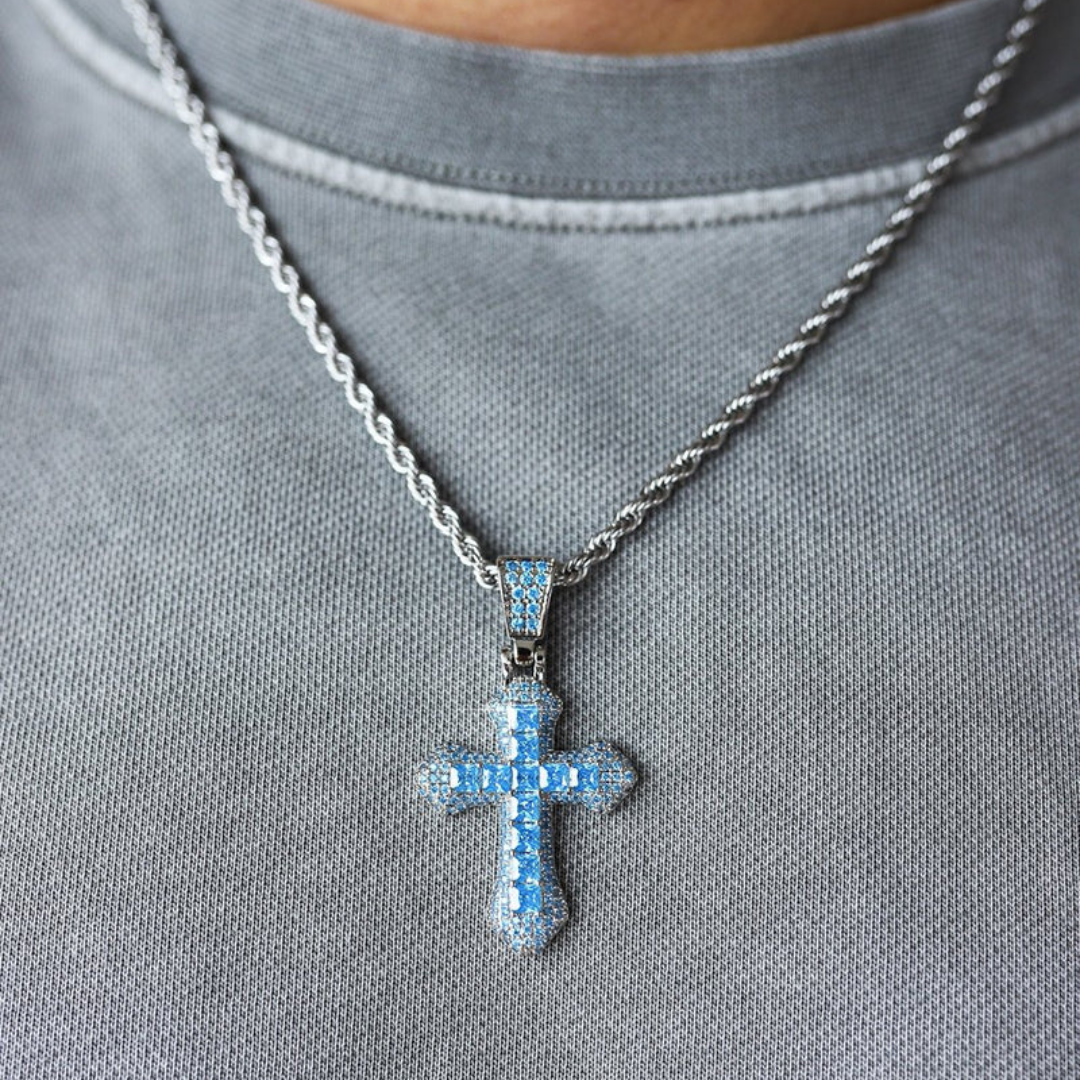 Model wearing a white gold cross pendant with striking blue gemstones, displayed on a delicate chain around the neck, complementing a stylish and elegant outfit.