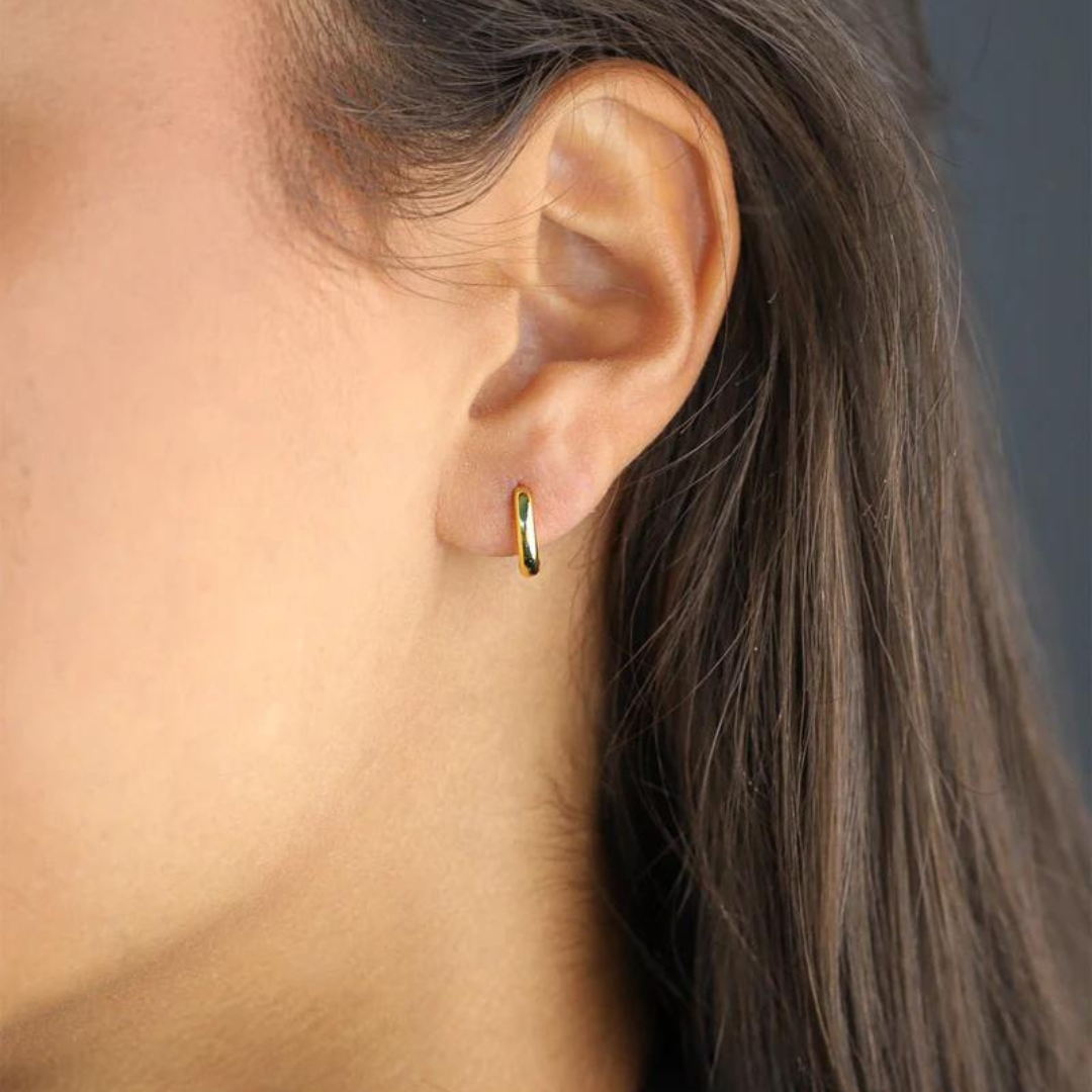 Women's model wearing the Solid Hoop Earrings in 925 Sterling Silver with a 14K Gold finish, emphasizing their elegant design and luxurious finish for a chic and sophisticated appearance.