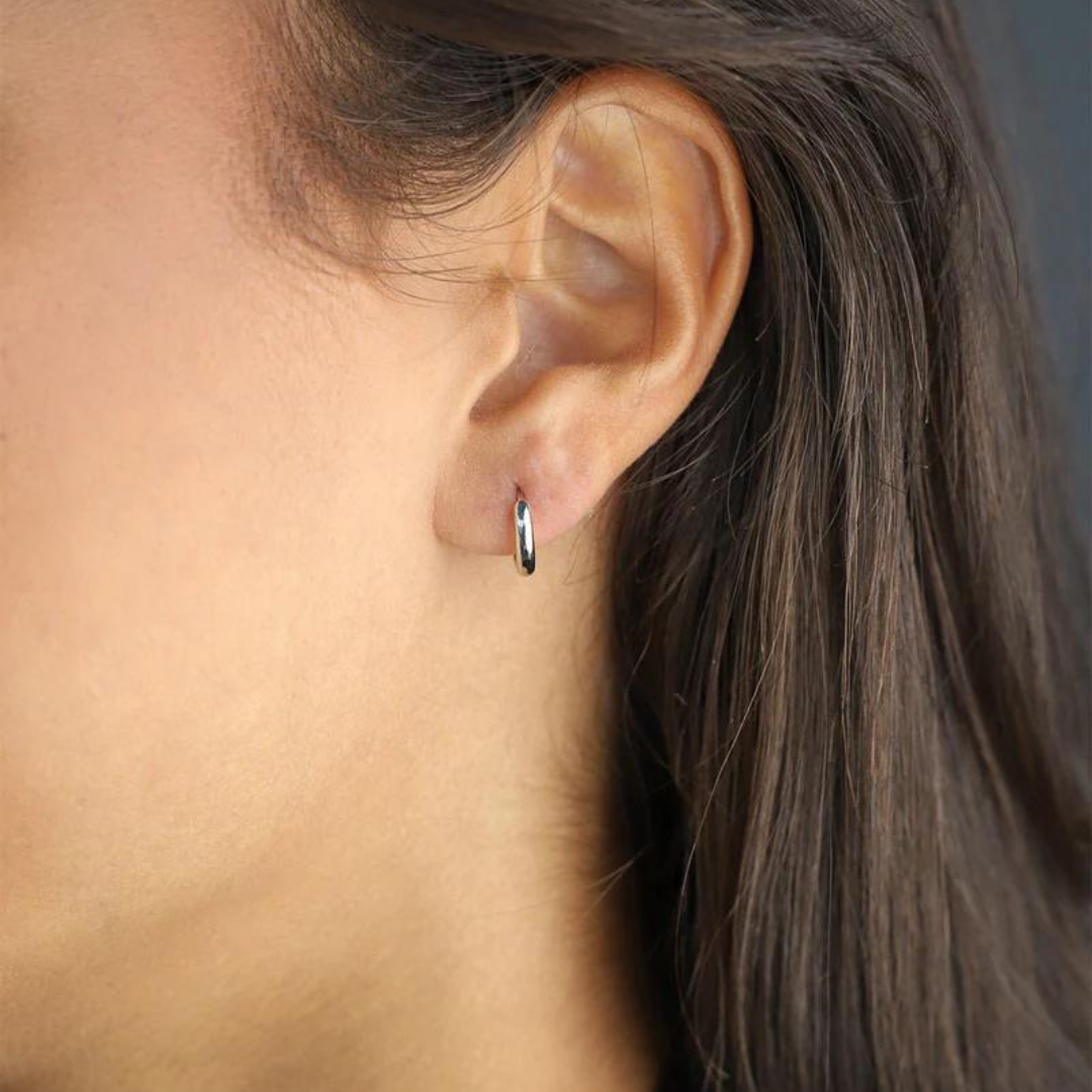 Women's model wearing the Solid Hoop Earrings in 925 Sterling Silver with a White Gold finish, emphasizing their elegant design and luxurious look for a chic and refined appearance.