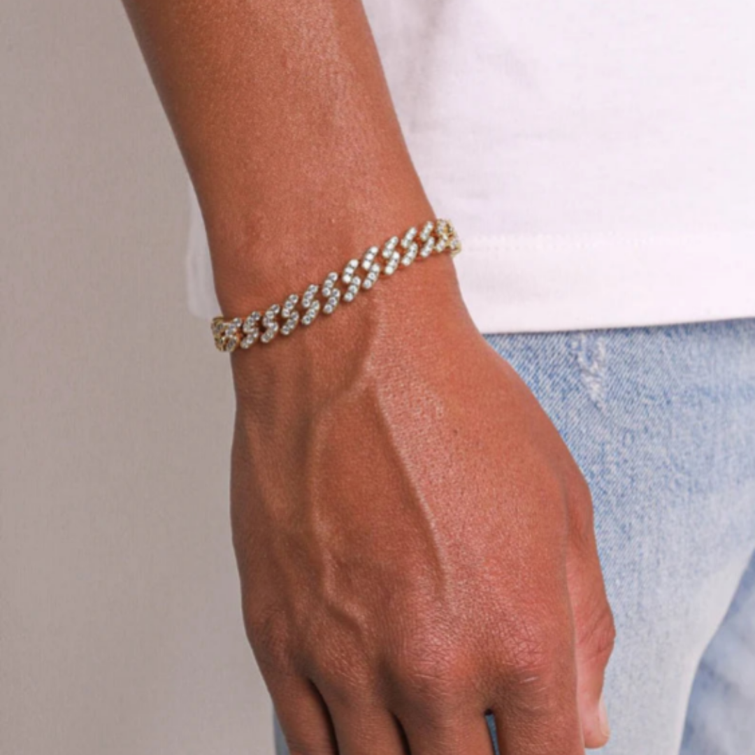 Men's model wearing an 18k gold iced Cuban link bracelet with a 9mm width, highlighting the dazzling stones and elegant shine against a sophisticated outfit.