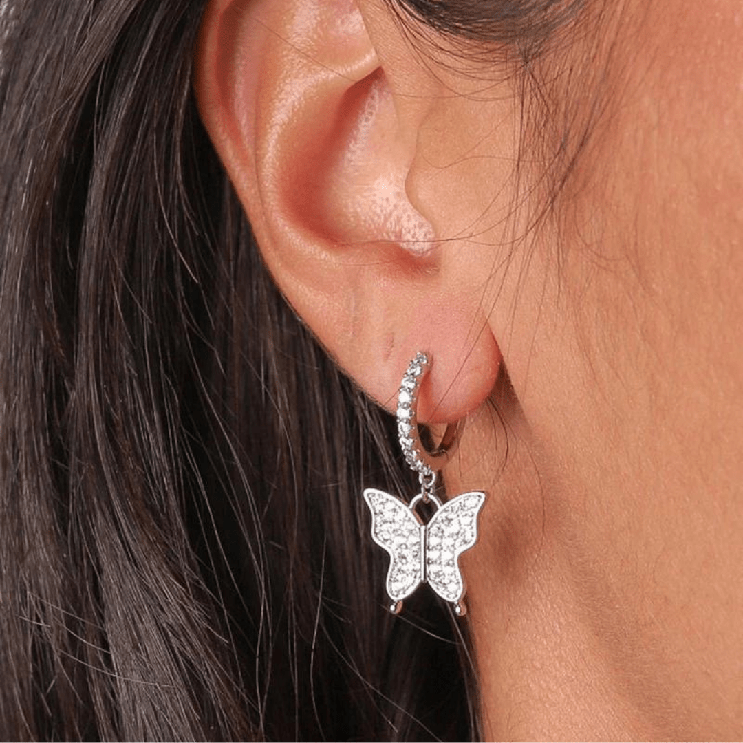 Model wearing white gold butterfly earrings, highlighting their intricate design and refined shine against a stylish outfit.