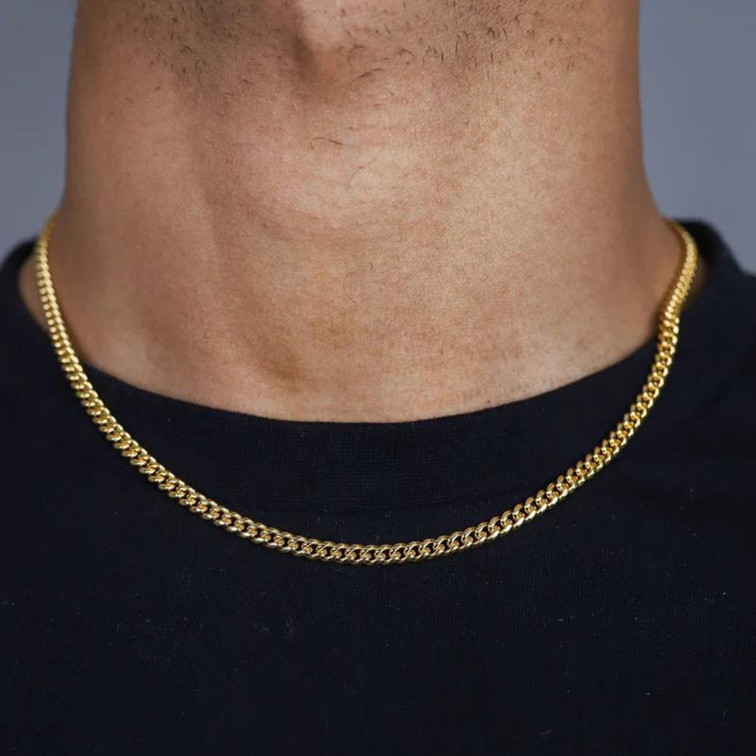 Mens model wearing an 18k gold Cuban link chain with a 3mm width, highlighting its subtle design and luxurious shine against a chic and modern outfit.